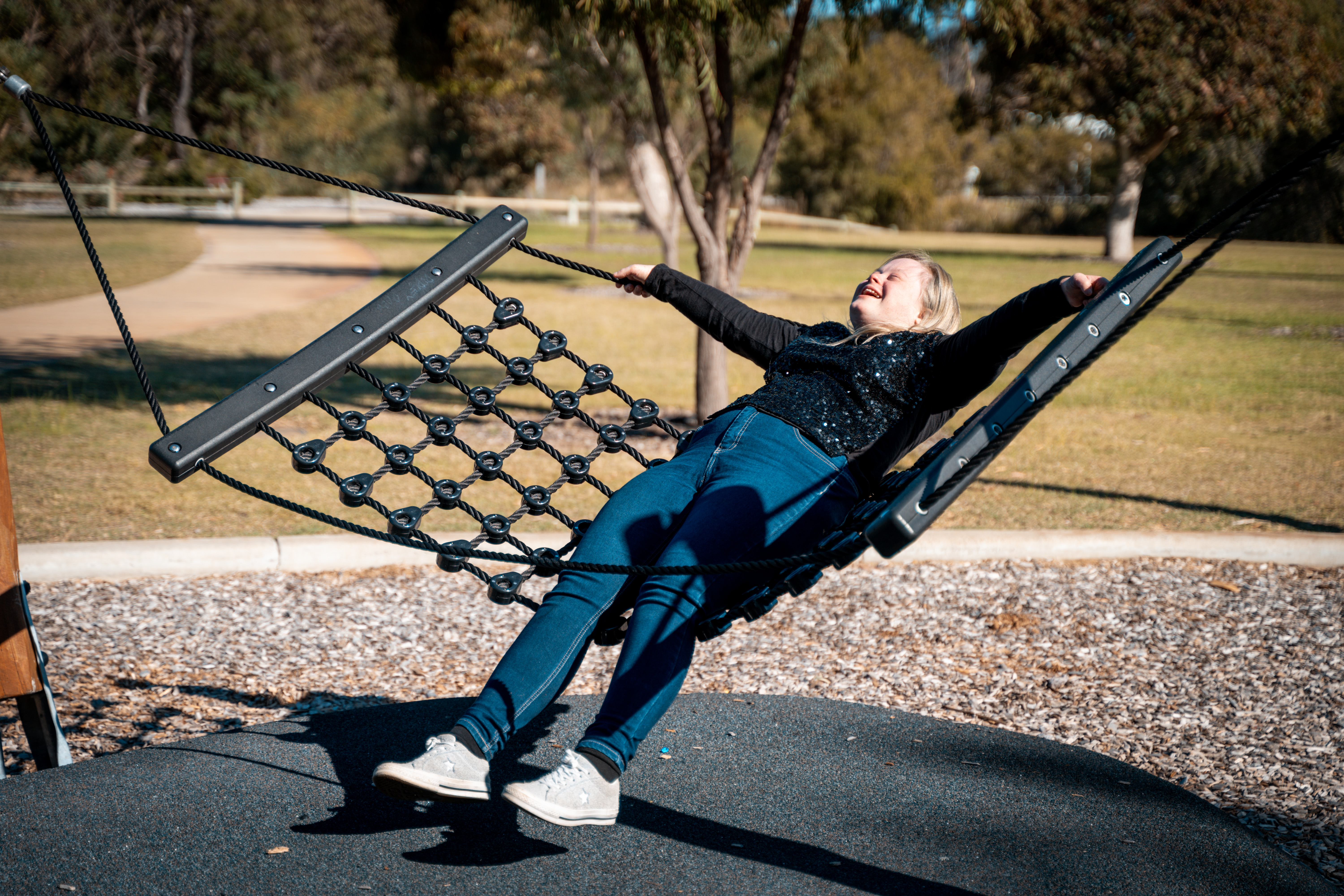 Person with Down syndrome enjoying an accessible playground hammock. 
